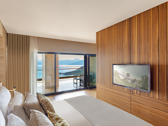 The entertainment area of a junior suite at D Maris Bay resort, where guests can sit and watch television. A window overlooks the sea view of the resort.  