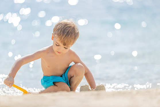 A young boy dressed in swimwear plays in the sand at the D Maris Bay resort.