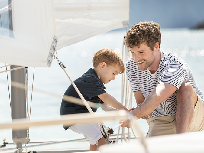  A father helps his young son to adjust the sail on their private yacht rental at the D Maris Bay resort.
