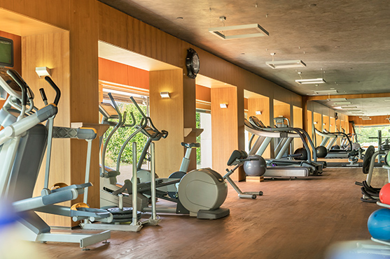 A view of the indoor fitness facilities at D Gym at D Maris Bay resort. A range of fitness machines face outwards to the view of the resort in clean, modern wooden gym. 